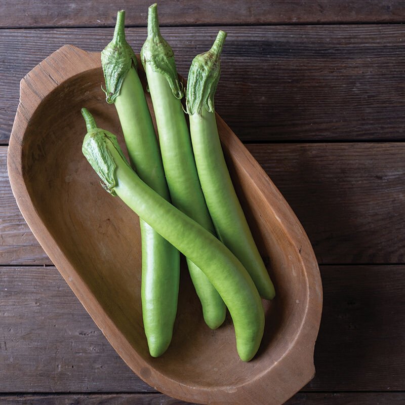Fresh green long beans arranged in a wooden bowl on a rustic wooden surface, showcasing their vibrant color and smooth texture, ideal for healthy cooking and recipes.